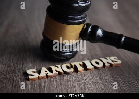 Immagine ravvicinata del martelletto del giudice e SANZIONI di testo su un tavolo di legno. Foto Stock