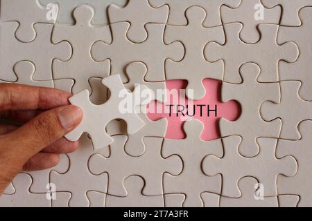Immagine ravvicinata del puzzle di raccolta delle mani e rivelare la parola VERITÀ. Foto Stock