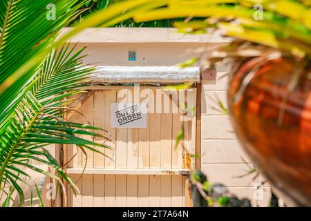 Porta in legno color sabbia sulla recinzione in cemento chiusa con serratura, testo fuori servizio, giorno di sole. Vista frontale ravvicinata Foto Stock