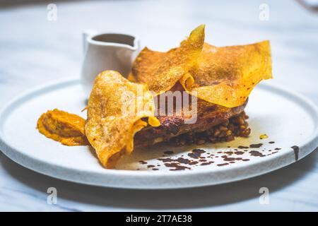 48 ore di confit di gambe di anatra essiccate all'aria, glassa di miele piccante, fogli di patate, fricasse di farro e funghi, jus tamarindo Foto Stock