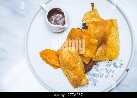 48 ore di confit di gambe di anatra essiccate all'aria, glassa di miele piccante, fogli di patate, fricasse di farro e funghi, jus tamarindo Foto Stock