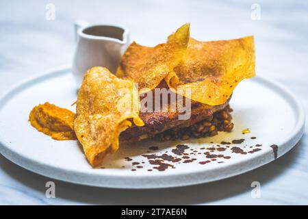 48 ore di confit di gambe di anatra essiccate all'aria, glassa di miele piccante, fogli di patate, fricasse di farro e funghi, jus tamarindo Foto Stock