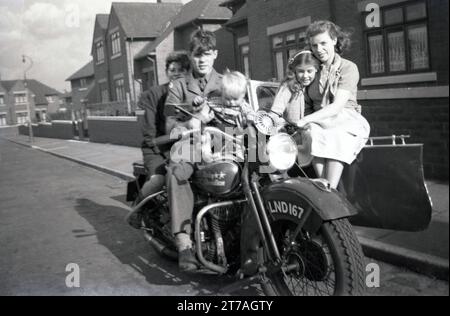 Anni '1950, storica, fuori in una strada, una famiglia seduta su una motocicletta Harley Davidson e sidecar di produzione americana dell'epoca per una foto, Oldham, Inghilterra, Regno Unito. Foto Stock