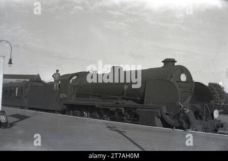 1950, storica, una locomotiva a vapore dell'epoca, 30794, in attesa presso una piattaforma ferroviaria, Inghilterra, Regno Unito. La locomotiva 4-6-0 King Arthur Class entrò in servizio nel 1926 per la Southern Railways (794) prima di essere rinumerata nel 30794 quando la British Railways fu costituita nel 1949. Fu ritirata nel 1960. Foto Stock