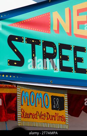 Segno pubblicitario colorato di Uno stand di Street Food Selling Momo, Christchurch Food Festival, Christchurch UK Foto Stock