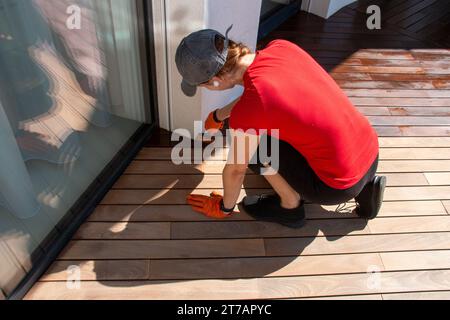 Rinfrescare un ponte in legno, lavoratrice che applica il sigillante per ponti con un pennello Foto Stock