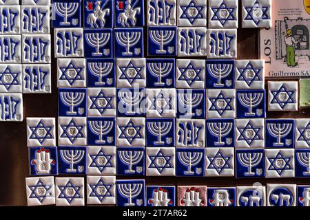 Toledo, Spagna, 08.10.21. Mostra di souvenir con piastrelle magnetiche bianche e blu con simboli ebraici: menorah, Stella di Davide e simbolo della N Foto Stock