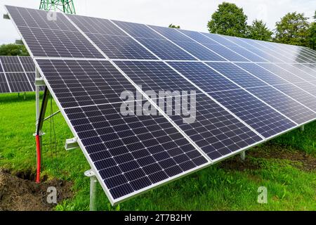 Installazione di pannelli solari su telai metallici in un prato verde, impianto solare incompiuto Foto Stock