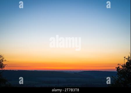 Un tramonto colorato sul South Downs National Park visto da Butser Hill, Queen Elizabeth Country Park, Hampshire, Inghilterra, Regno Unito Foto Stock