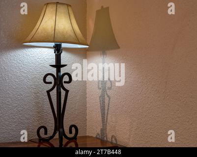 Lampada da tavolo illuminata nell'angolo di una camera da letto con un'ombra sulla parete Foto Stock