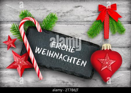 Frohe Weihnachten und rote Dekoration Herz, Tannenzweige, Zuckerstange und Label auf Holz Foto Stock