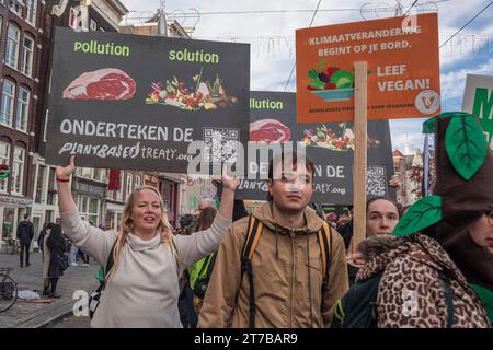 Amsterdam, Paesi Bassi. 12 novembre 2023. I manifestanti hanno dei cartelli che esprimono la loro opinione durante la manifestazione. Si stima che 85.000 manifestanti abbiano partecipato a una marcia pacifica sul clima senza arresti. Questo ha superato la dimostrazione climatica di due anni fa, che ha avuto 45.000 partecipanti. I dimostranti hanno percorso un percorso da Piazza Dam al Museumplein. Sulla loro strada si unirono a una grande marcia filo-palestinese. Tra i manifestanti c'era l'attivista per il clima svedese Greta Thunberg, in seguito tenne un breve discorso sul Museumplein. La marcia è stata organizzata da nove organizzazioni, sotto il nome Foto Stock