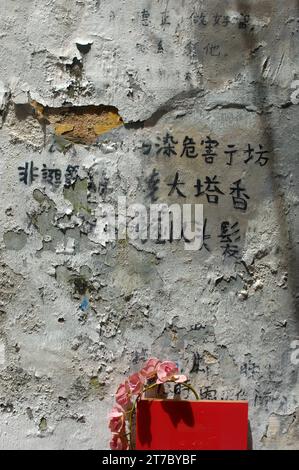 Caratteri cinesi scritti su un muro di vernice sbucciante, Macao, Cina. Foto Stock