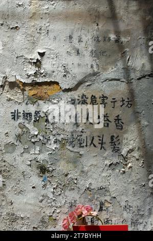 Caratteri cinesi scritti su un muro di vernice sbucciante, Macao, Cina. Foto Stock