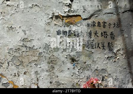 Caratteri cinesi scritti su un muro di vernice sbucciante, Macao, Cina. Foto Stock