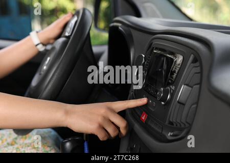 Scelta della radio preferita. Donna che preme il pulsante sull'audio del veicolo in auto, primo piano Foto Stock