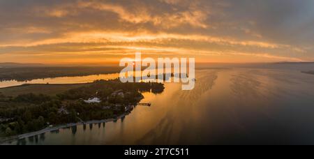 Panorama aereo del Lago di Costanza occidentale all'alba con la penisola di Mettnau, con spiaggia balneabile, pontile e ristorante Strandcafè, sul Foto Stock