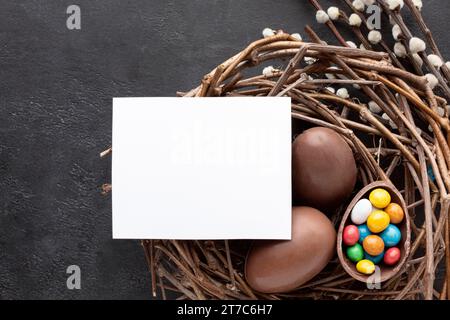 Uova di pasqua al cioccolato a base piatta ripiene di colorato nido di caramelle Foto Stock