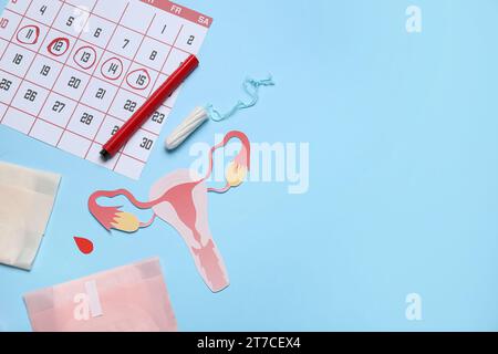 Composizione con utero di carta, calendario mestruale e prodotti per l'igiene femminile su sfondo colorato Foto Stock