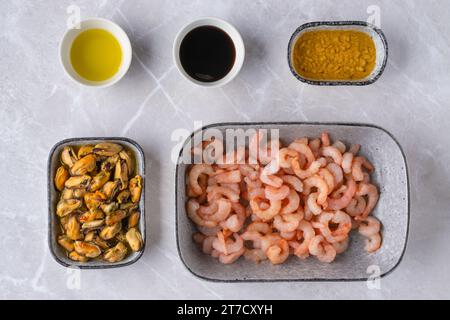 Vista dall'alto delle ciotole con gamberetti sbucciati, cozze, salse e olio d'aglio Foto Stock