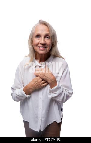 Donna matura europea felice di 65 anni che indossa una camicia su sfondo bianco Foto Stock