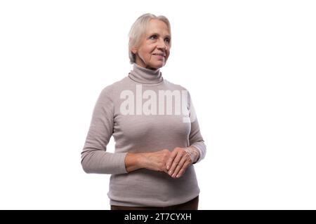 Una donna pensionata di 65 anni con un taglio di capelli corto guarda con attenzione di lato Foto Stock