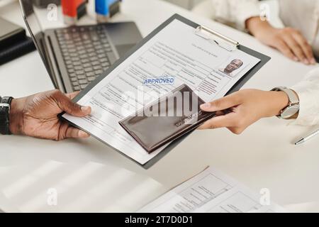 Primo piano di un uomo che ottiene i suoi documenti approvati per il visto in agenzia per i visti Foto Stock