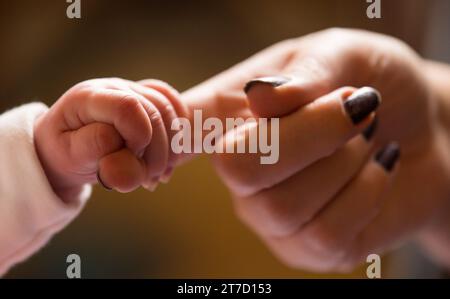 Foto del fascicolo datata 23/01/16 di un nuovo bambino che tiene il dito della madre. Tre quarti (75%) delle madri single potrebbero lottare per permettersi le basi come il cibo e il riscaldamento quando vanno in pensione, secondo un rapporto. Data di emissione: Mercoledì 15 novembre 2023. Foto Stock