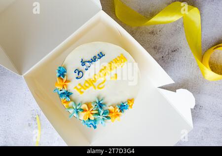 Torta bento alla moda con un'iscrizione blu-gialla in ucraino "buon compleanno" su sfondo chiaro. Torta di compleanno, torta Bento per due Ukrai Foto Stock