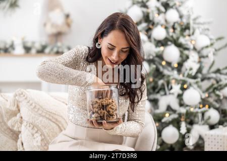 La donna è eccitante a prendere un biscotto dal barattolo durante il Natale. Foto Stock