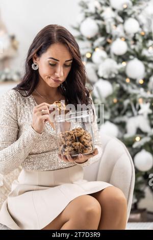 Donna infelice per gli irresistibili biscotti con gocce di cioccolato che tira fuori dal vaso. Foto Stock