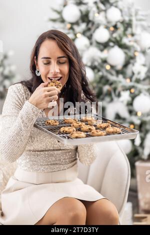 Le donne apprezzano i sapori dei biscotti di Natale appena sfornati direttamente dal vassoio Foto Stock