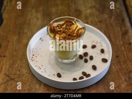 Dolce tiramisù in una tazza su un tavolo di legno Foto Stock