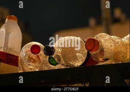 Più contenitori di plastica per bevande sono posizionati in posizione orizzontale sopra un cestino coperto da gocce di pioggia. Foto Stock