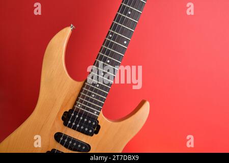 Dettaglio di corpo in legno e collo di chitarra elettrica isolato con sfondo rosso sfumato. Vista frontale Foto Stock