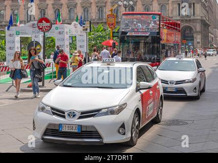 Milano, Italia - 15 giugno 2019: Veicoli ibridi bianchi ed elettrici in taxi presso la strada nel centro della città il giorno d'estate. Foto Stock