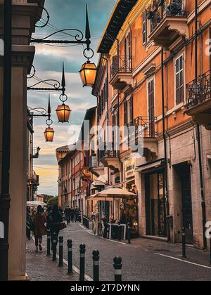 Una stretta strada urbana illuminata da una serie di lampioni circondati da alti edifici di mattoni rossi Foto Stock