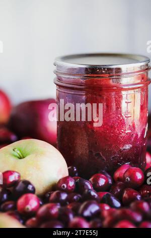 Conserve di mele al mirtillo fatte in casa con frutta fresca. Messa a fuoco selettiva con sfocatura estrema in primo piano e sfondo. Foto Stock