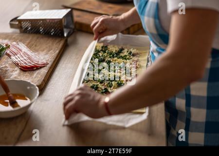 Il cuoco prepara pasta sfoglia con pancetta, spinaci e formaggio e prepara piccole torte per pizza. Procedura di ricetta: 5 di 10 Foto Stock