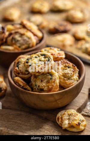 Mini panini per pizza ripieni di vari ingredienti, prosciutto pancetta spinaci, basilico, mozzarella o parmigiano in una ciotola di legno. Foto Stock