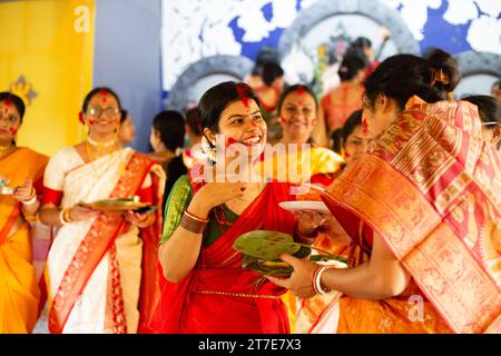 Birbhum, Bengala Occidentale, India - 24 ottobre 2023: Una bella donna in abito tradizionale con faccia sorridente di colore rosso che gioca con sindoor durante l'ultimo Foto Stock