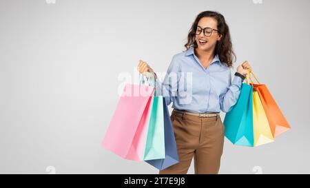 Allegra signora caucasica millenaria in abbigliamento formale, occhiali con bocca aperta Foto Stock