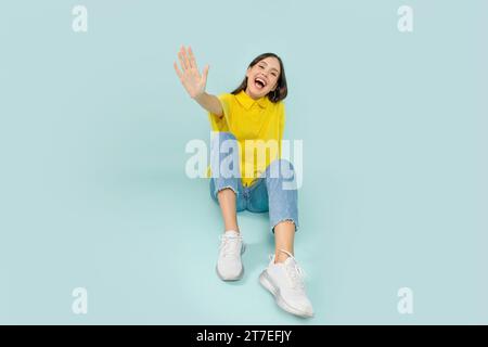 Gioiosa giovane bruna seduta a terra e ridendo Foto Stock