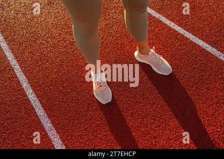 Primo piano delle gambe dell'atleta sulla linea di partenza della pista da corsa Foto Stock