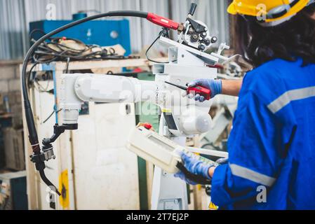 Ingegneri meccanici di squadra che utilizzano un controller computerizzato braccio robotico per la saldatura dell'acciaio in un'officina siderurgica. Software di programmazione per robot industriali per aut Foto Stock