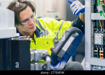 Tester di lavoro per ingegnere elettrico che misura la tensione e la  corrente della linea elettrica di alimentazione nel controllo di armadi  elettrici per la produzione industriale Foto stock - Alamy