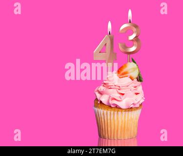 Torta di compleanno con candela numero 43 - su sfondo rosa caldo. Foto Stock