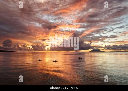 Cielo e mare in colori spettacolari al tramonto con persone in barca, impressionante formazione di nuvole e in montagna sullo sfondo, riflesso, intenso Foto Stock