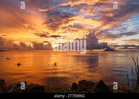 Tramonto con colori spettacolari sulla costa di Sulawesi, colori intensi riflessi nell'acqua, tre barche da pesca pittoresche in primo piano Foto Stock