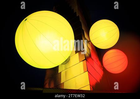 le lanterne cinesi illuminate gialle e arancioni si avvicinano a un muro metallizzato. Foto Stock